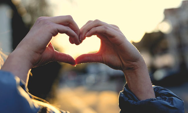 Hands forming a heart shape, backlit by sunlight